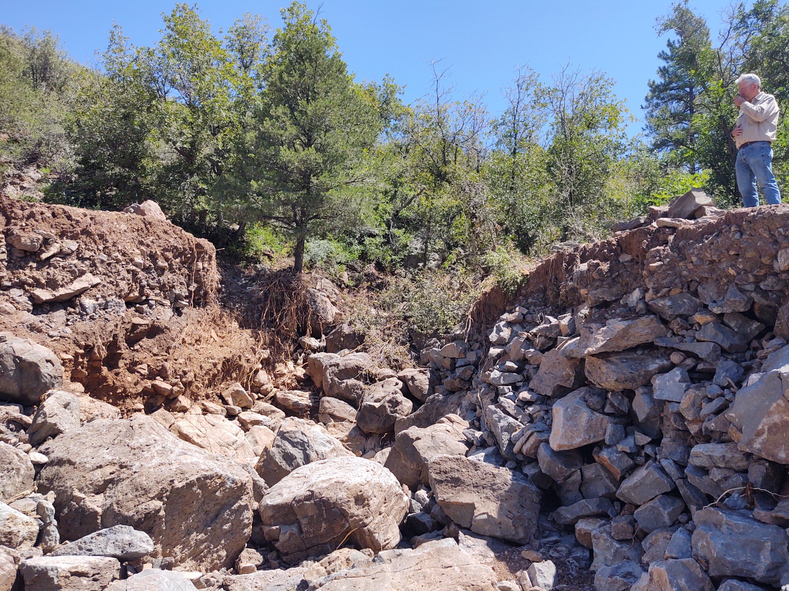 Coconino/Kaibab Zone Forest Engineer, John O’Brien, stands at the edge of a washed-out portion of Forest Road 354. The gap is approximately 15-20 feet deep and 30-50 feet across.   